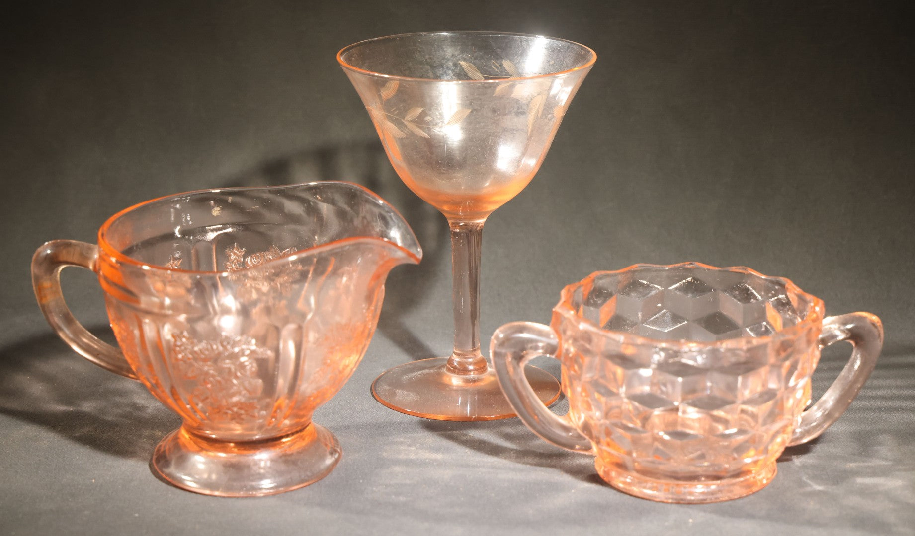 Trio of Vintage Pink Depression Glass Including Floral Relief Creamer, Cubist Open Sugar, and Etched Champagne Coupe
