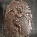 Lot 083 - Antique Cast Iron Oval Wall Plaque of Cupid with Bow and Arrow, Shell and Crown Crest, Note Loss to Top of Bow, 3-1/2" W x 6" H