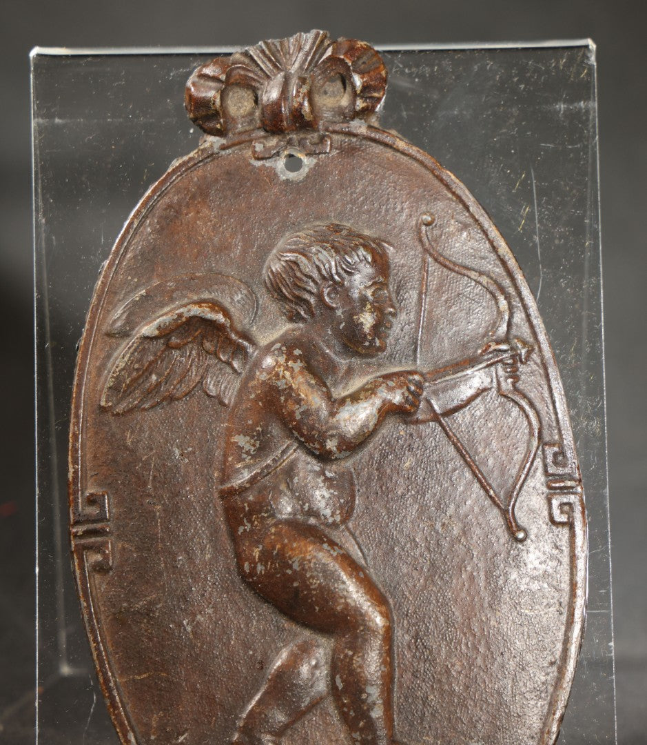 Antique Cast Iron Oval Wall Plaque of Cupid with Bow and Arrow, Shell and Crown Crest, Note Loss to Top of Bow
