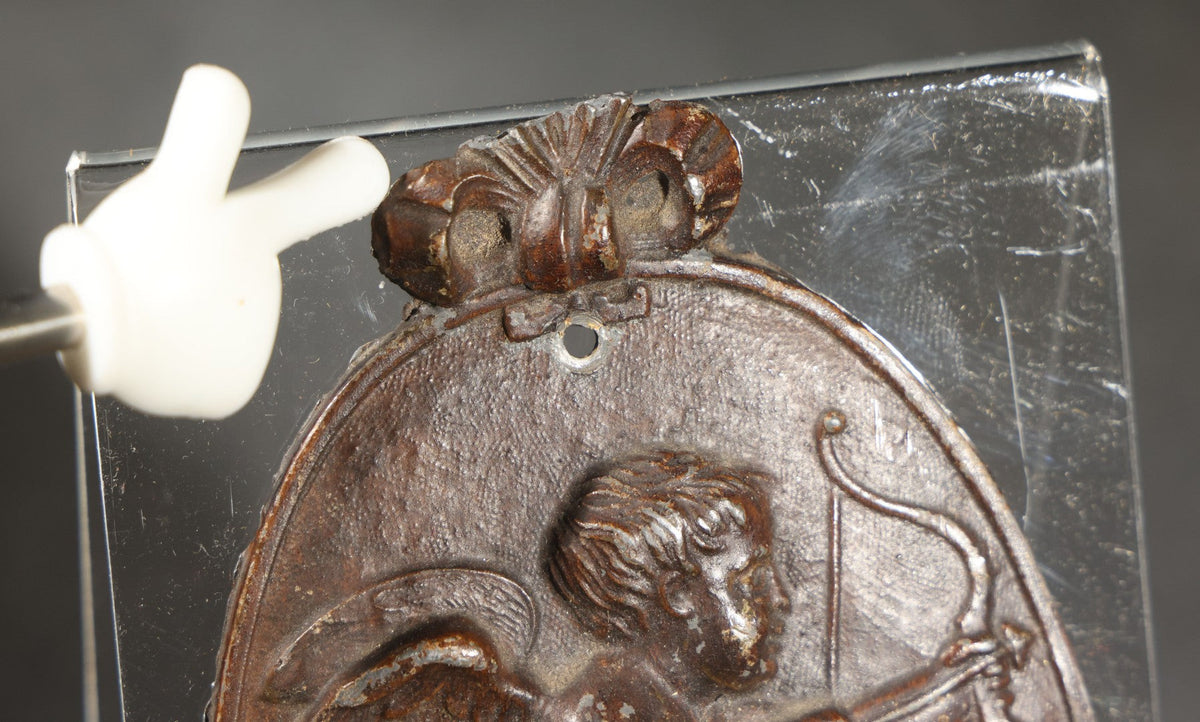 Antique Cast Iron Oval Wall Plaque of Cupid with Bow and Arrow, Shell and Crown Crest, Note Loss to Top of Bow