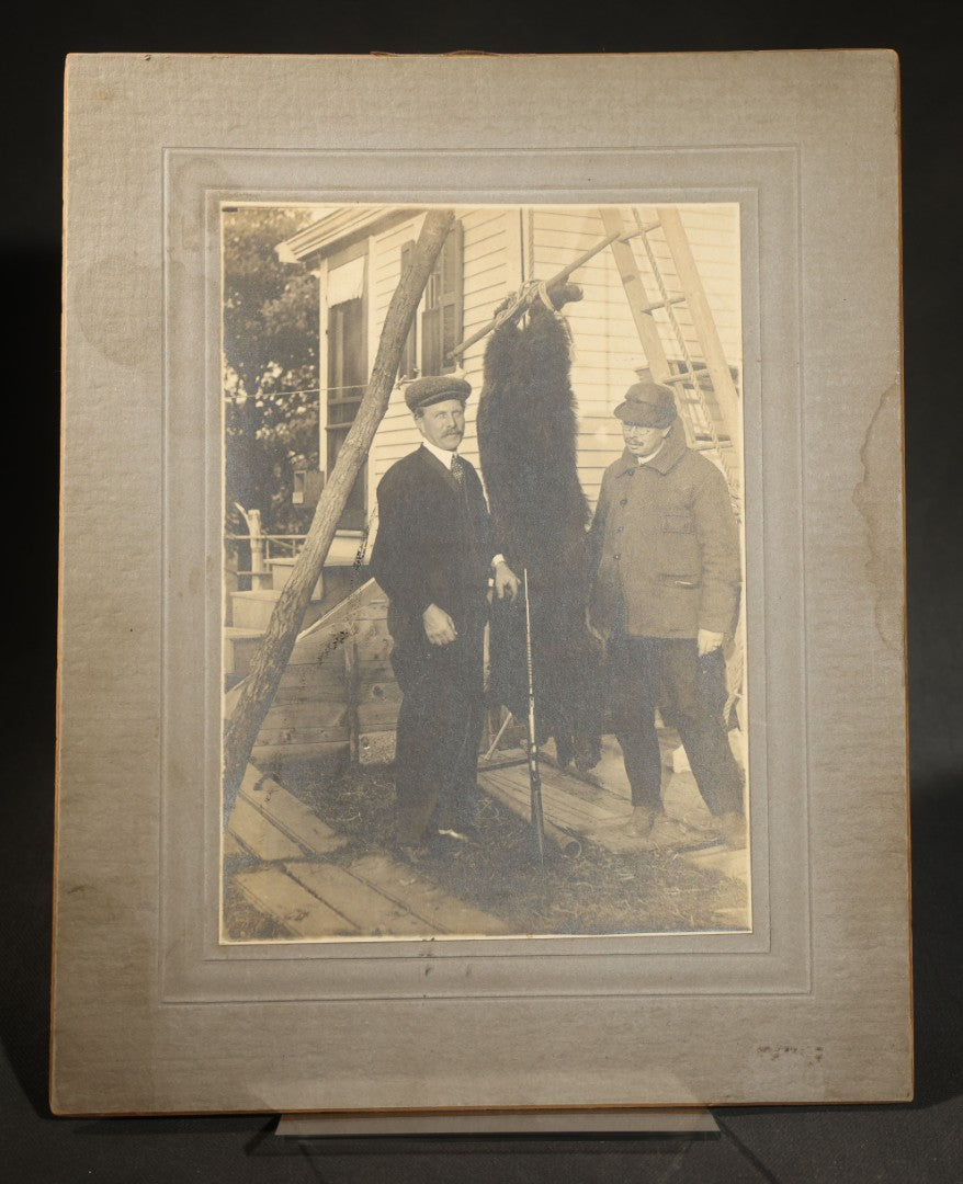 Antique Board-Mounted Photograph of Two Hunters Posing with a Hanging Black Bear