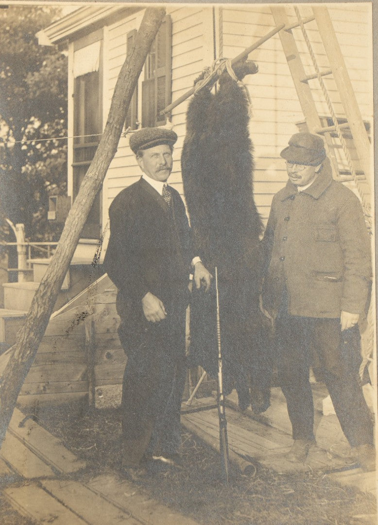 Antique Board-Mounted Photograph of Two Hunters Posing with a Hanging Black Bear