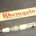 Lot 062 - Pair of Vintage Advertising Items, Rheingold Beer Foam Scraper and Lion Head Motor Oil Pencil with real oil sample
