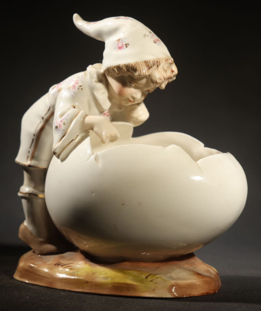 Antique Porcelain Figurine of Child in Stocking Cap Looking into Large Egg, Manufactured by Gebruder Heubach, Lichten, Germany, Note Chip