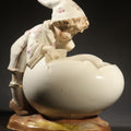 Lot 028 - Antique Porcelain Figurine of Child in Stocking Cap Looking Into Large Egg, Manufactured by Gebruder Heubach, Lichten, Germany, Note Chip, 5-1/4" H