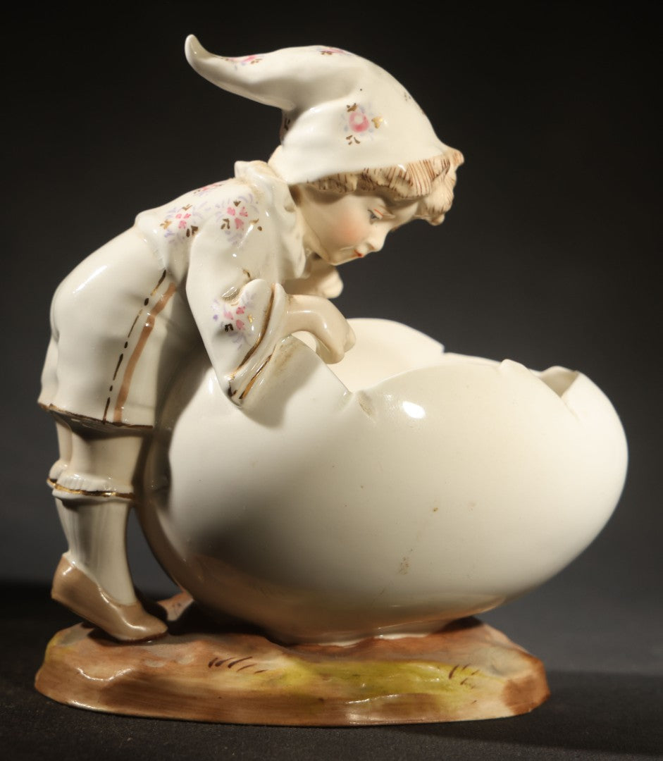 Antique Porcelain Figurine of Child in Stocking Cap Looking into Large Egg, Manufactured by Gebruder Heubach, Lichten, Germany, Note Chip