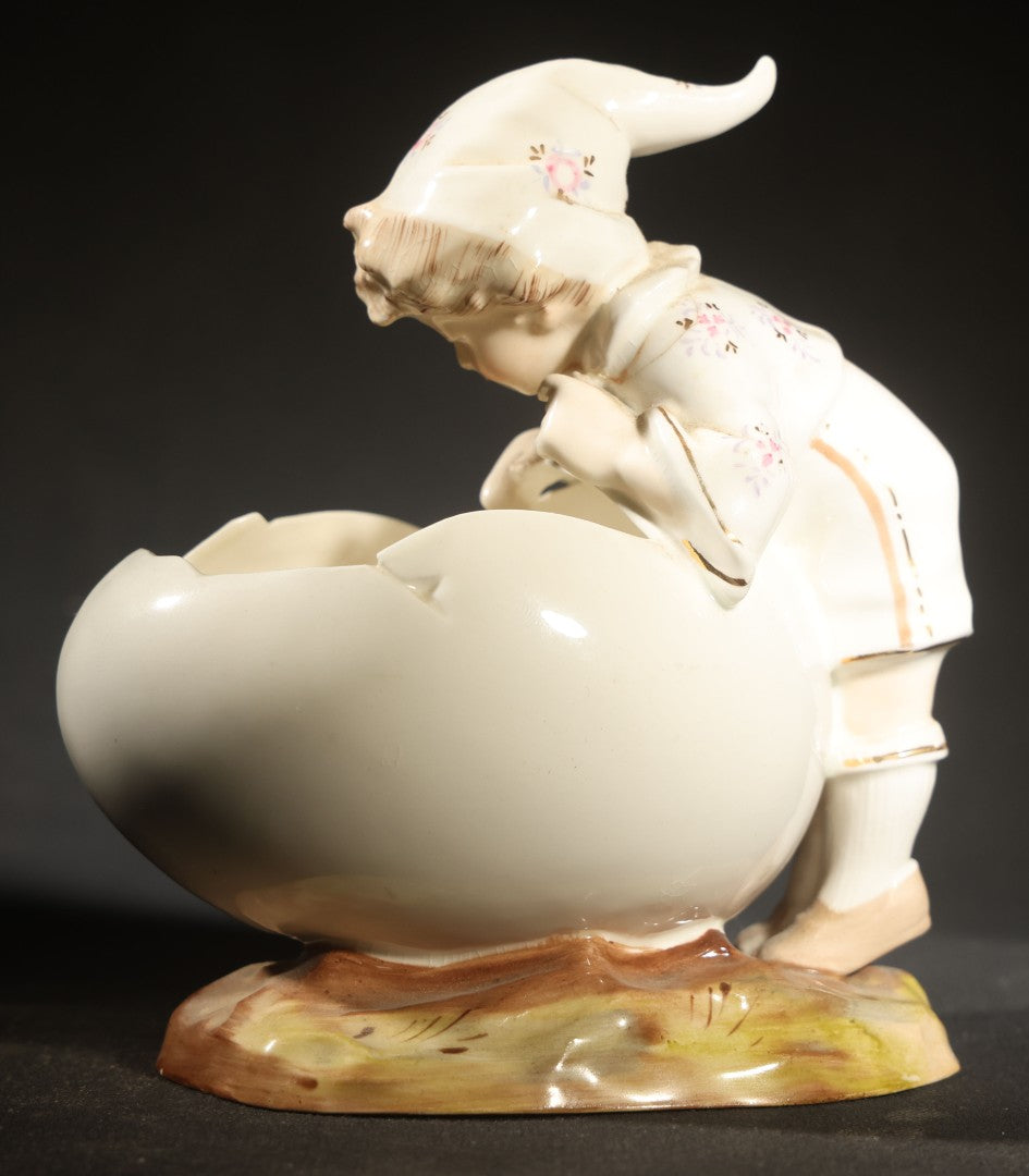 Antique Porcelain Figurine of Child in Stocking Cap Looking into Large Egg, Manufactured by Gebruder Heubach, Lichten, Germany, Note Chip