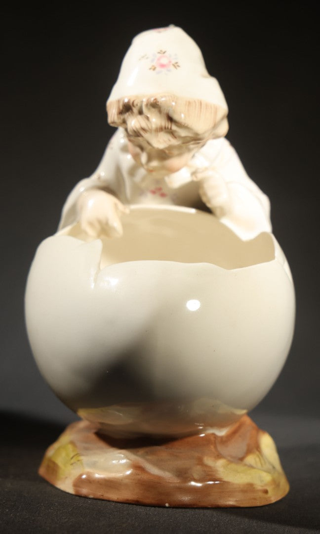 Antique Porcelain Figurine of Child in Stocking Cap Looking into Large Egg, Manufactured by Gebruder Heubach, Lichten, Germany, Note Chip
