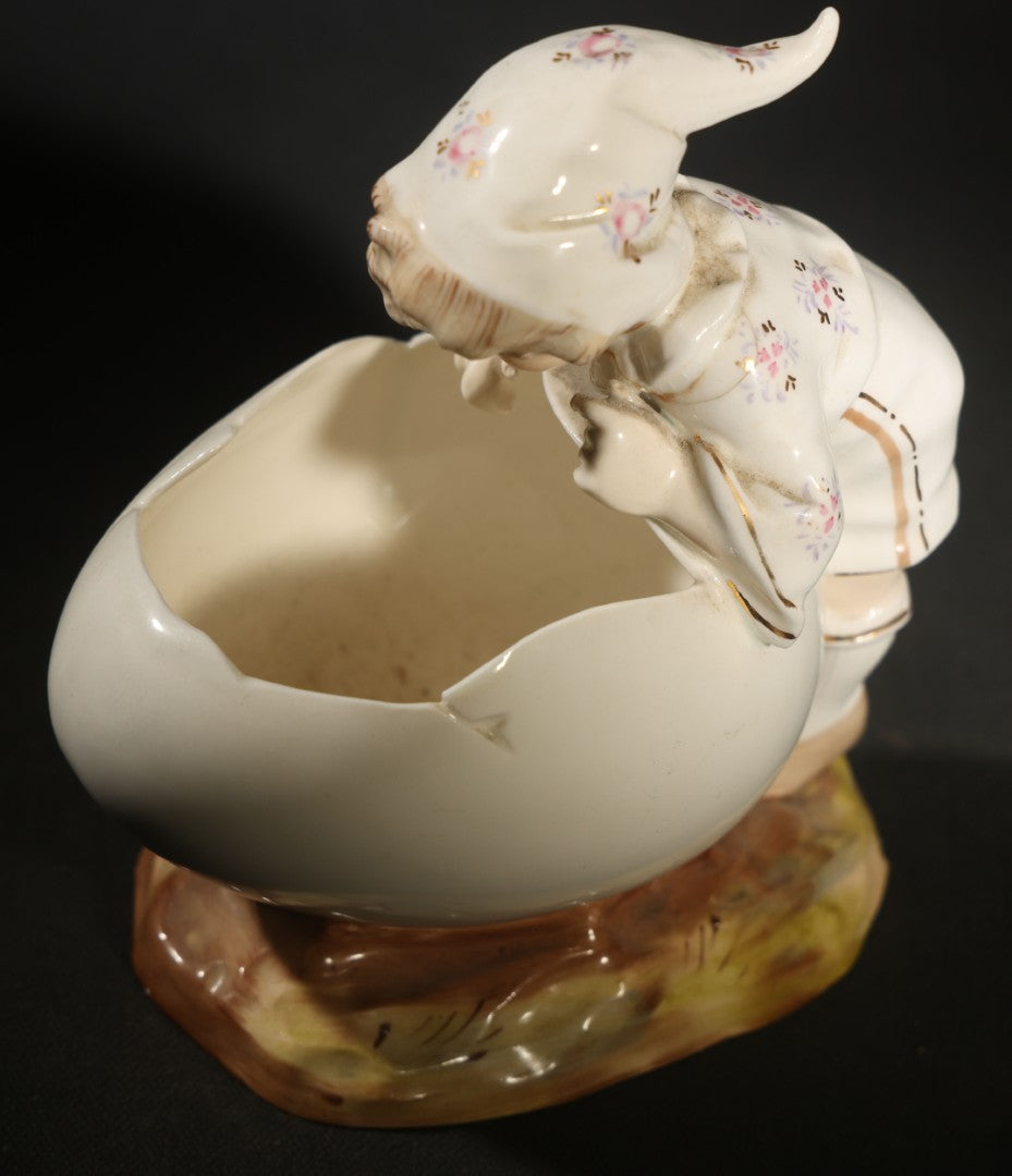 Antique Porcelain Figurine of Child in Stocking Cap Looking into Large Egg, Manufactured by Gebruder Heubach, Lichten, Germany, Note Chip