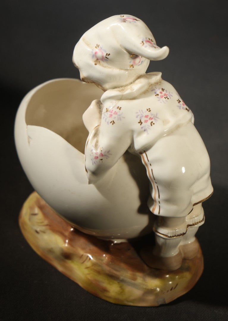 Antique Porcelain Figurine of Child in Stocking Cap Looking into Large Egg, Manufactured by Gebruder Heubach, Lichten, Germany, Note Chip