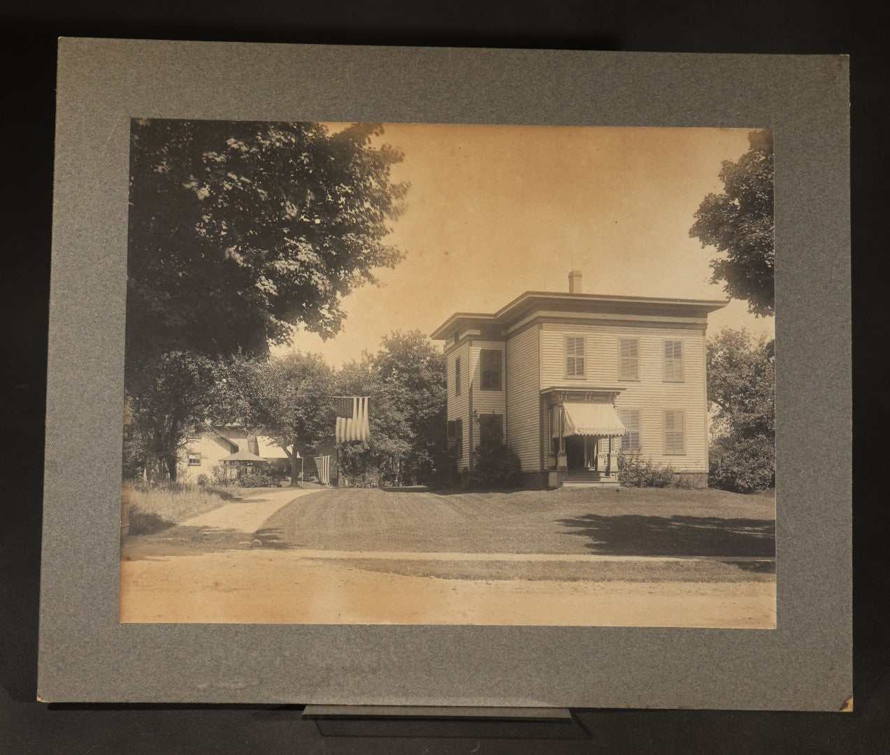 Trio of Vintage Board-Mounted Photographs Including Two-Story House with American Flags, Multi-Story Industrial Building with Gathered Crowd and High Wheel Bicycle, and Small Railroad Depot