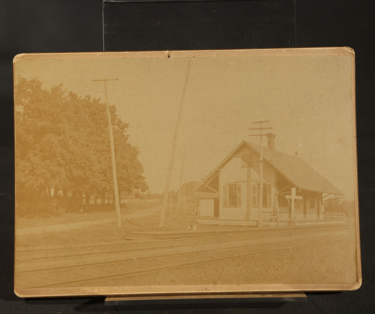 Trio of Vintage Board-Mounted Photographs Including Two-Story House with American Flags, Multi-Story Industrial Building with Gathered Crowd and High Wheel Bicycle, and Small Railroad Depot