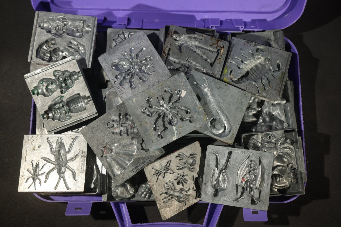 Grouping of 47 Vintage Creepy Crawler Metal Molds including Spiders, Skulls, Insects, and Monsters, Mostly Copyright 1994 by Toymax, with Purple Plastic Toymax Carrying Case