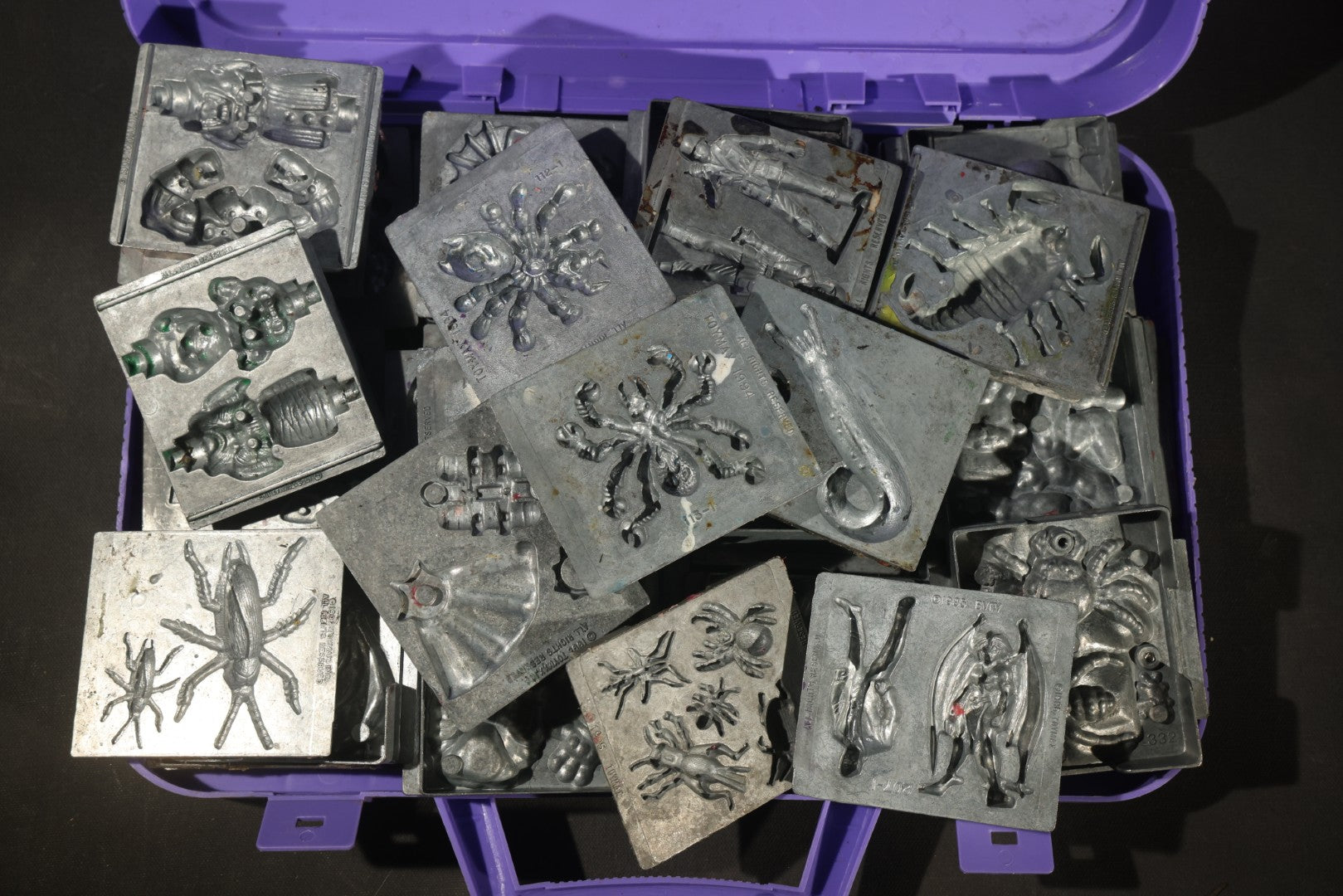 Grouping of 47 Vintage Creepy Crawler Metal Molds including Spiders, Skulls, Insects, and Monsters, Mostly Copyright 1994 by Toymax, with Purple Plastic Toymax Carrying Case