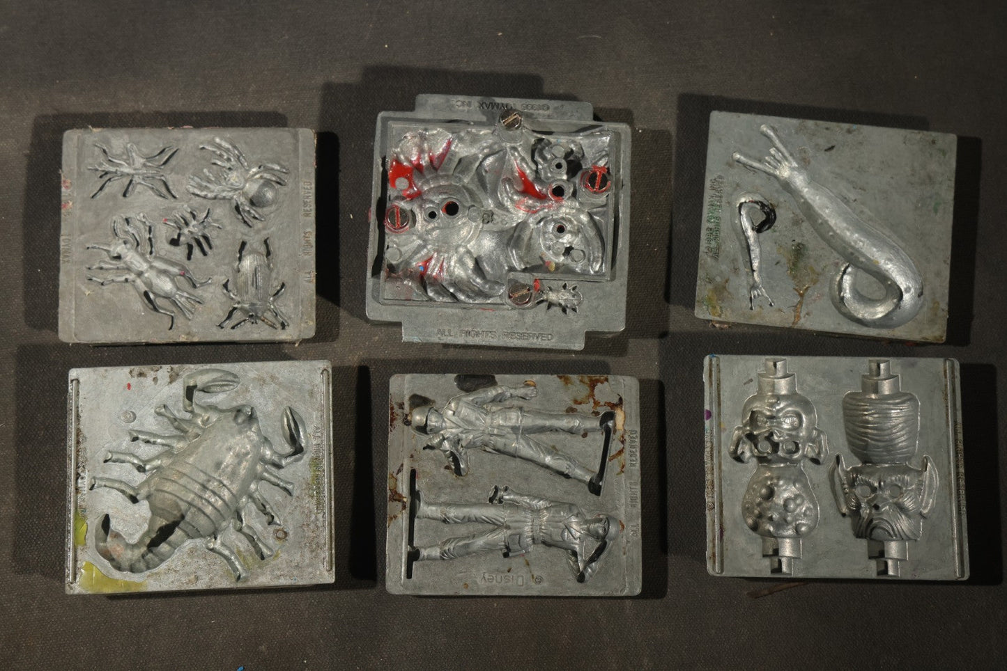 Grouping of 47 Vintage Creepy Crawler Metal Molds including Spiders, Skulls, Insects, and Monsters, Mostly Copyright 1994 by Toymax, with Purple Plastic Toymax Carrying Case