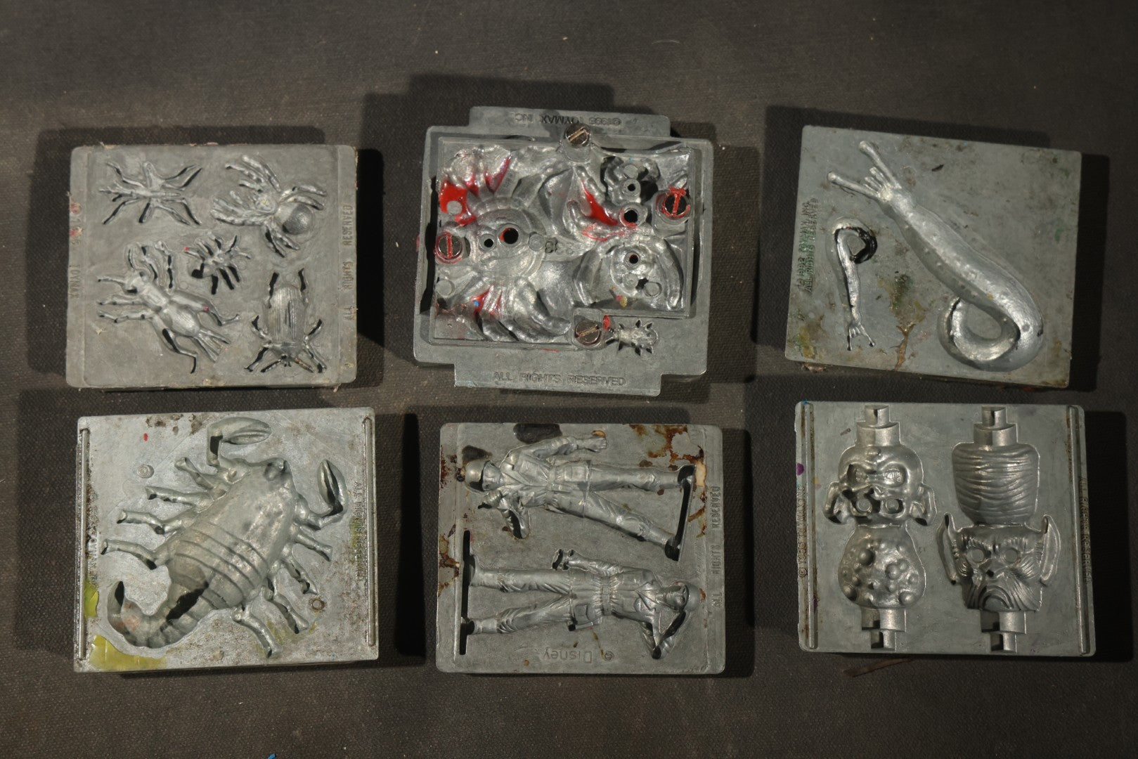 Grouping of 47 Vintage Creepy Crawler Metal Molds including Spiders, Skulls, Insects, and Monsters, Mostly Copyright 1994 by Toymax, with Purple Plastic Toymax Carrying Case