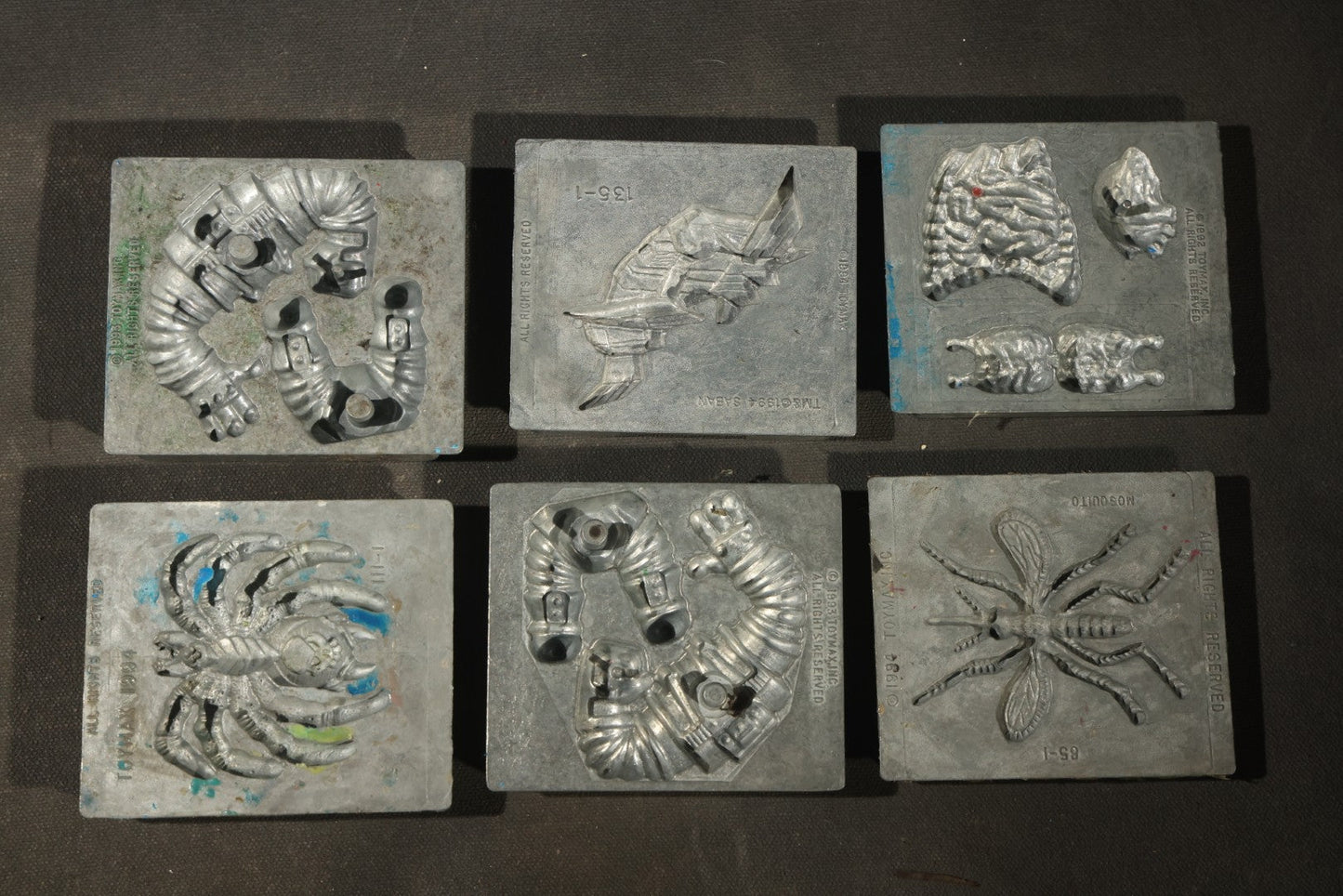 Grouping of 47 Vintage Creepy Crawler Metal Molds including Spiders, Skulls, Insects, and Monsters, Mostly Copyright 1994 by Toymax, with Purple Plastic Toymax Carrying Case