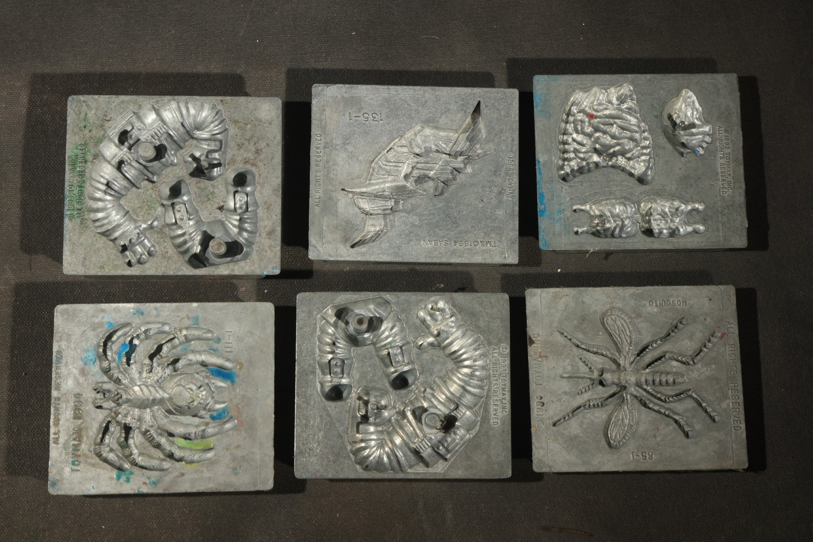 Grouping of 47 Vintage Creepy Crawler Metal Molds including Spiders, Skulls, Insects, and Monsters, Mostly Copyright 1994 by Toymax, with Purple Plastic Toymax Carrying Case