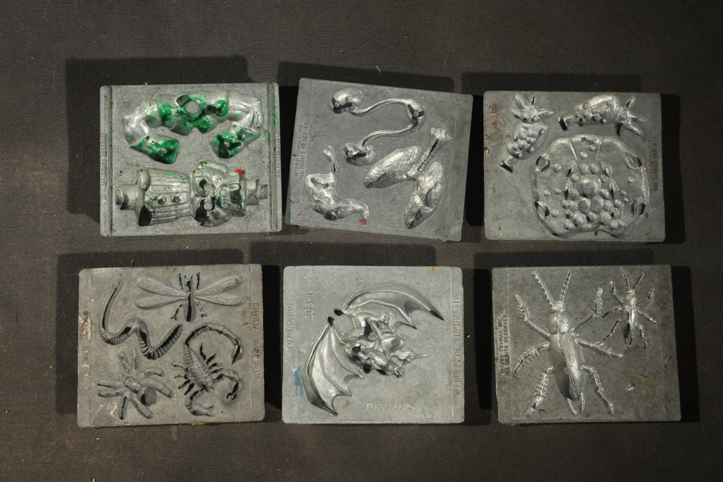 Grouping of 47 Vintage Creepy Crawler Metal Molds including Spiders, Skulls, Insects, and Monsters, Mostly Copyright 1994 by Toymax, with Purple Plastic Toymax Carrying Case