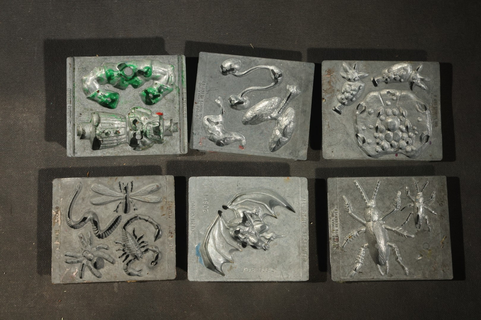 Grouping of 47 Vintage Creepy Crawler Metal Molds including Spiders, Skulls, Insects, and Monsters, Mostly Copyright 1994 by Toymax, with Purple Plastic Toymax Carrying Case