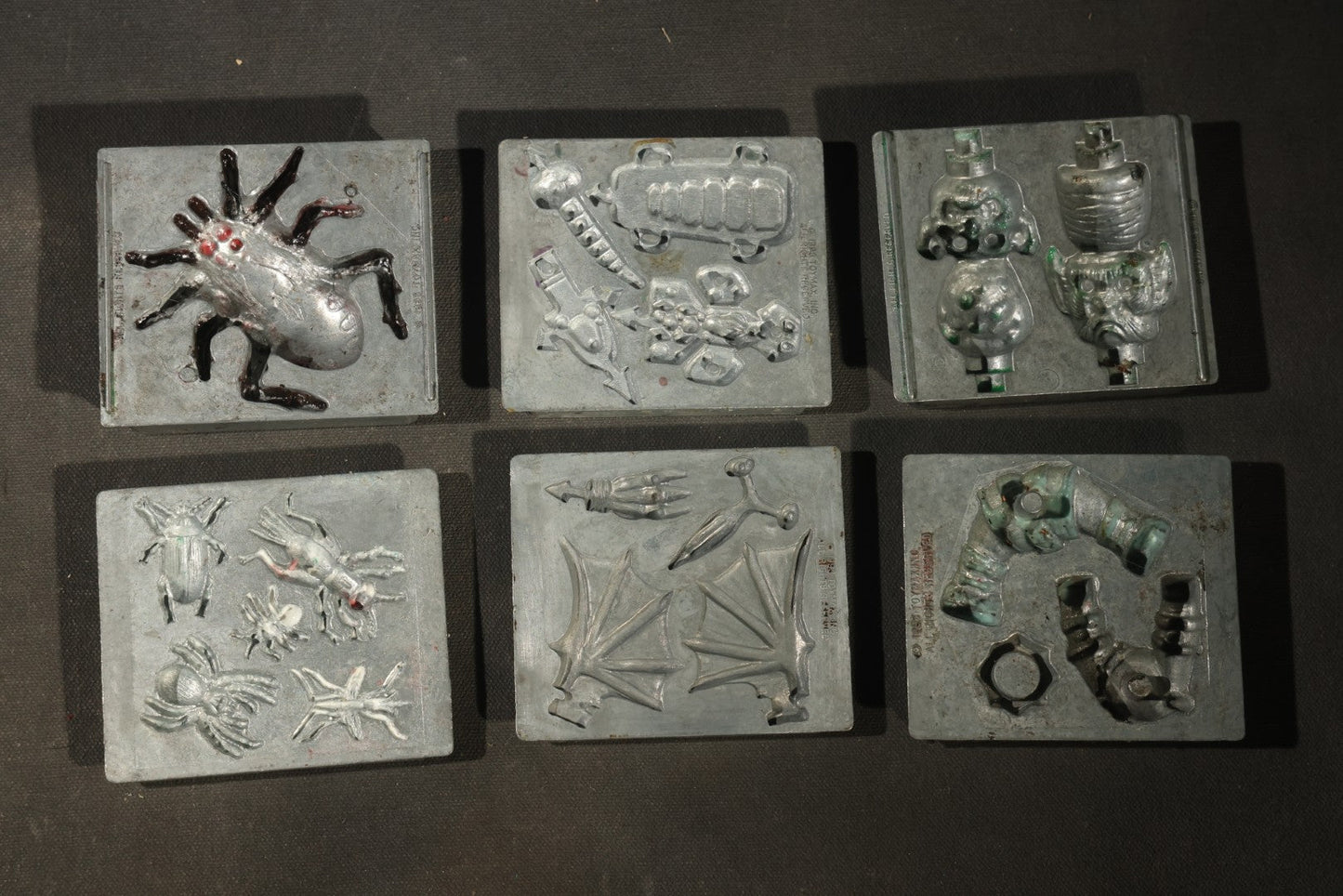 Grouping of 47 Vintage Creepy Crawler Metal Molds including Spiders, Skulls, Insects, and Monsters, Mostly Copyright 1994 by Toymax, with Purple Plastic Toymax Carrying Case