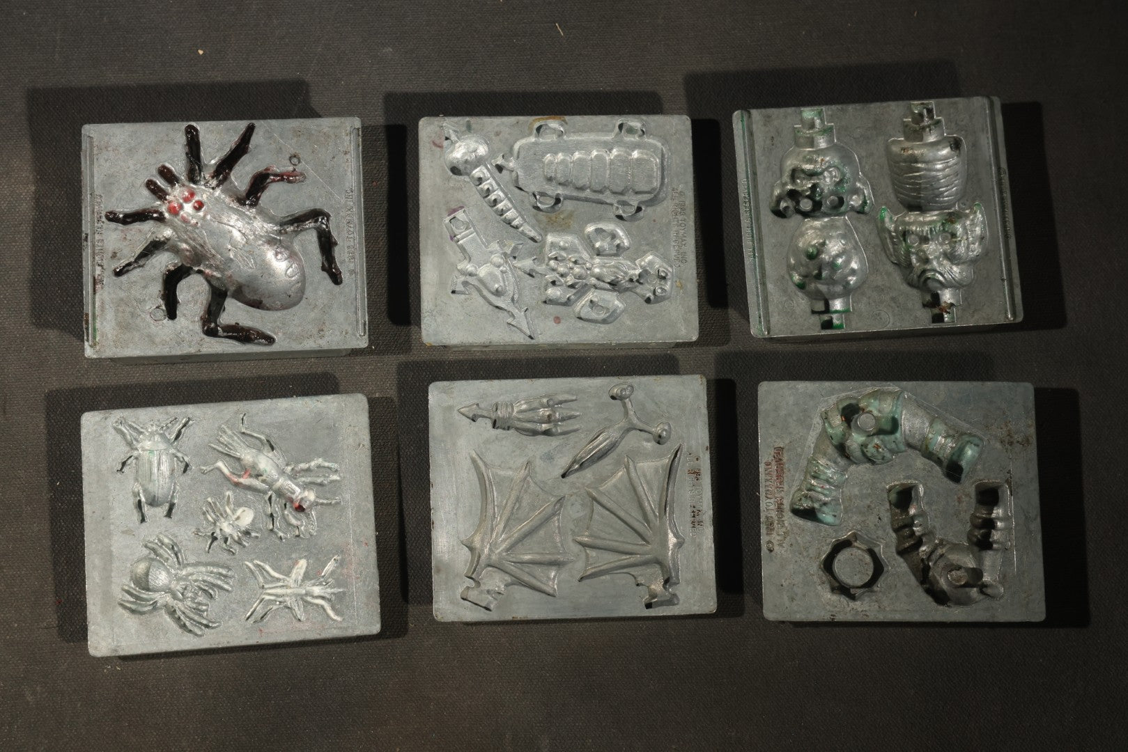 Grouping of 47 Vintage Creepy Crawler Metal Molds including Spiders, Skulls, Insects, and Monsters, Mostly Copyright 1994 by Toymax, with Purple Plastic Toymax Carrying Case