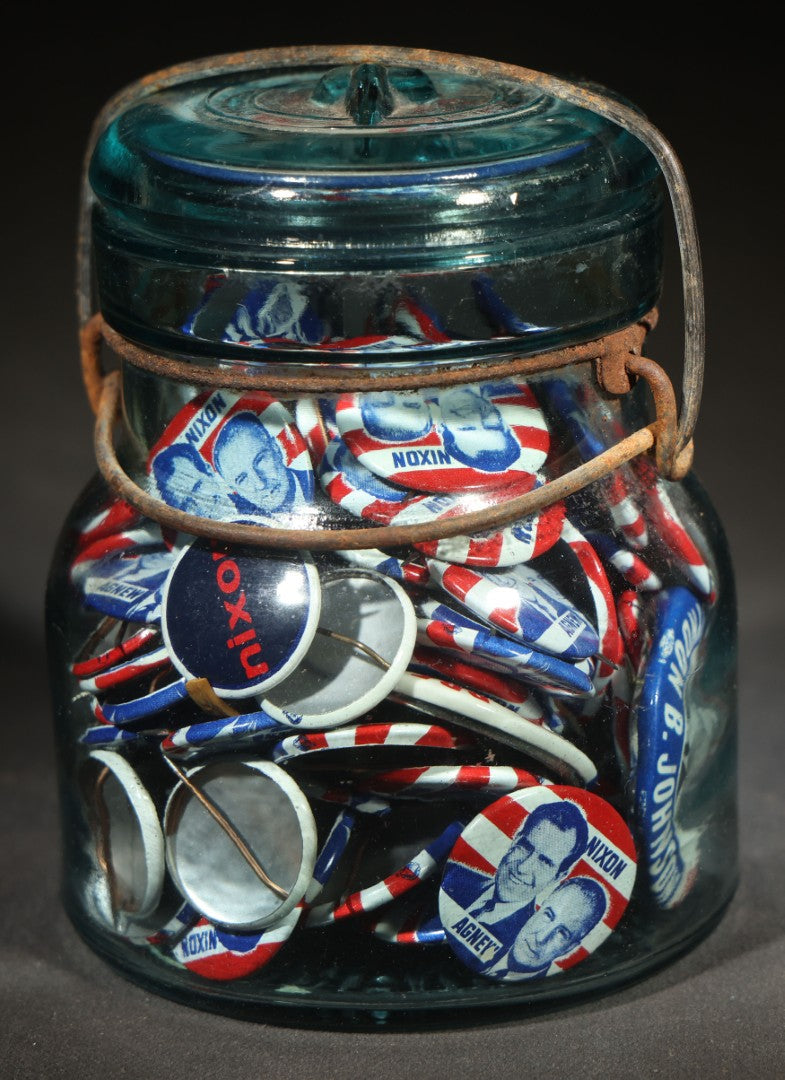 Grouping of Vintage Political Campaign Buttons and Pins including Nixon/Agnew, Johnson, Jimmy Carter Peanut Pins, and Lenticular "Nixon's the One!" Button in Wire Bail Glass Storage Jar