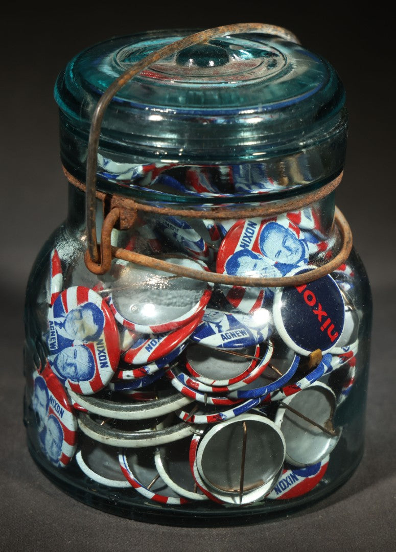 Grouping of Vintage Political Campaign Buttons and Pins including Nixon/Agnew, Johnson, Jimmy Carter Peanut Pins, and Lenticular "Nixon's the One!" Button in Wire Bail Glass Storage Jar