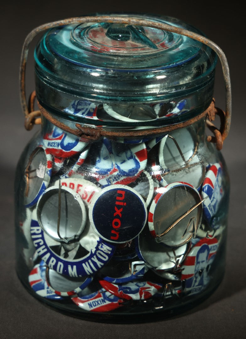 Grouping of Vintage Political Campaign Buttons and Pins including Nixon/Agnew, Johnson, Jimmy Carter Peanut Pins, and Lenticular "Nixon's the One!" Button in Wire Bail Glass Storage Jar