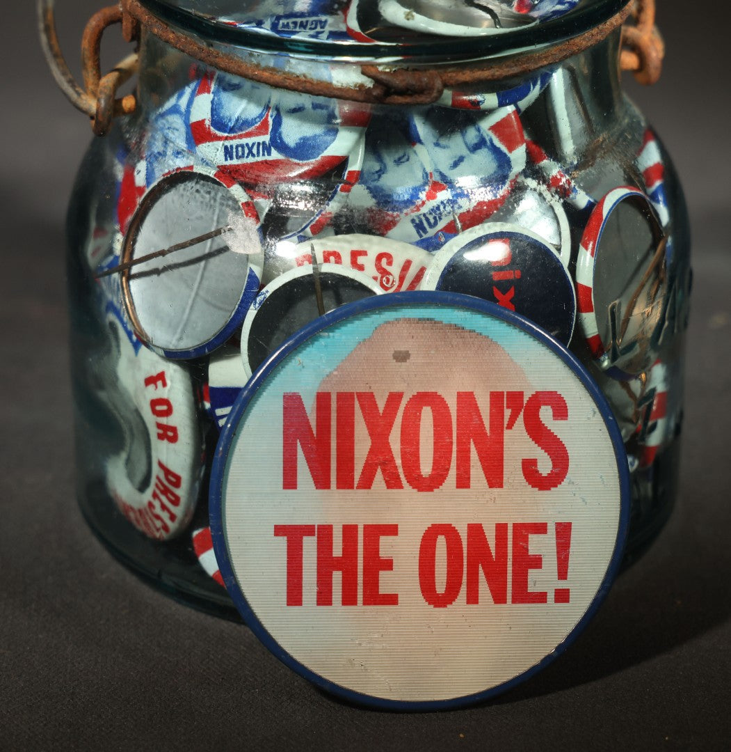 Grouping of Vintage Political Campaign Buttons and Pins including Nixon/Agnew, Johnson, Jimmy Carter Peanut Pins, and Lenticular "Nixon's the One!" Button in Wire Bail Glass Storage Jar