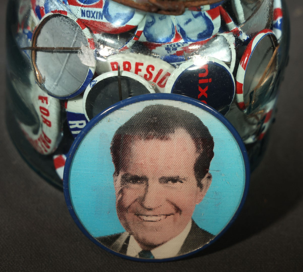 Grouping of Vintage Political Campaign Buttons and Pins including Nixon/Agnew, Johnson, Jimmy Carter Peanut Pins, and Lenticular "Nixon's the One!" Button in Wire Bail Glass Storage Jar