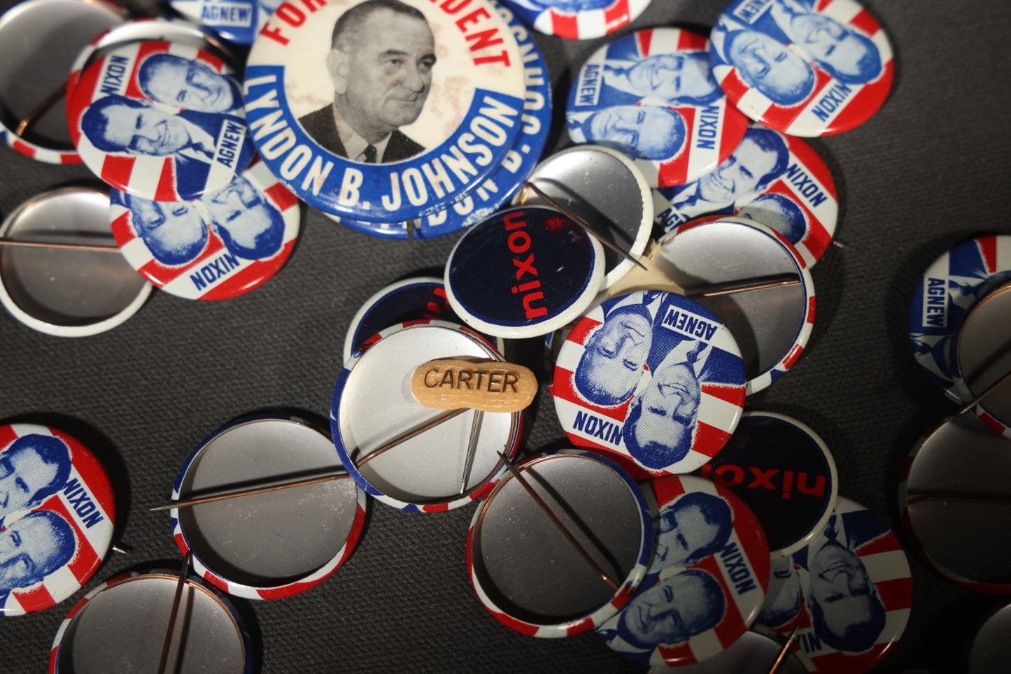 Grouping of Vintage Political Campaign Buttons and Pins including Nixon/Agnew, Johnson, Jimmy Carter Peanut Pins, and Lenticular "Nixon's the One!" Button in Wire Bail Glass Storage Jar