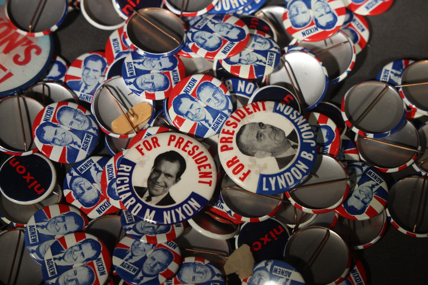 Grouping of Vintage Political Campaign Buttons and Pins including Nixon/Agnew, Johnson, Jimmy Carter Peanut Pins, and Lenticular "Nixon's the One!" Button in Wire Bail Glass Storage Jar