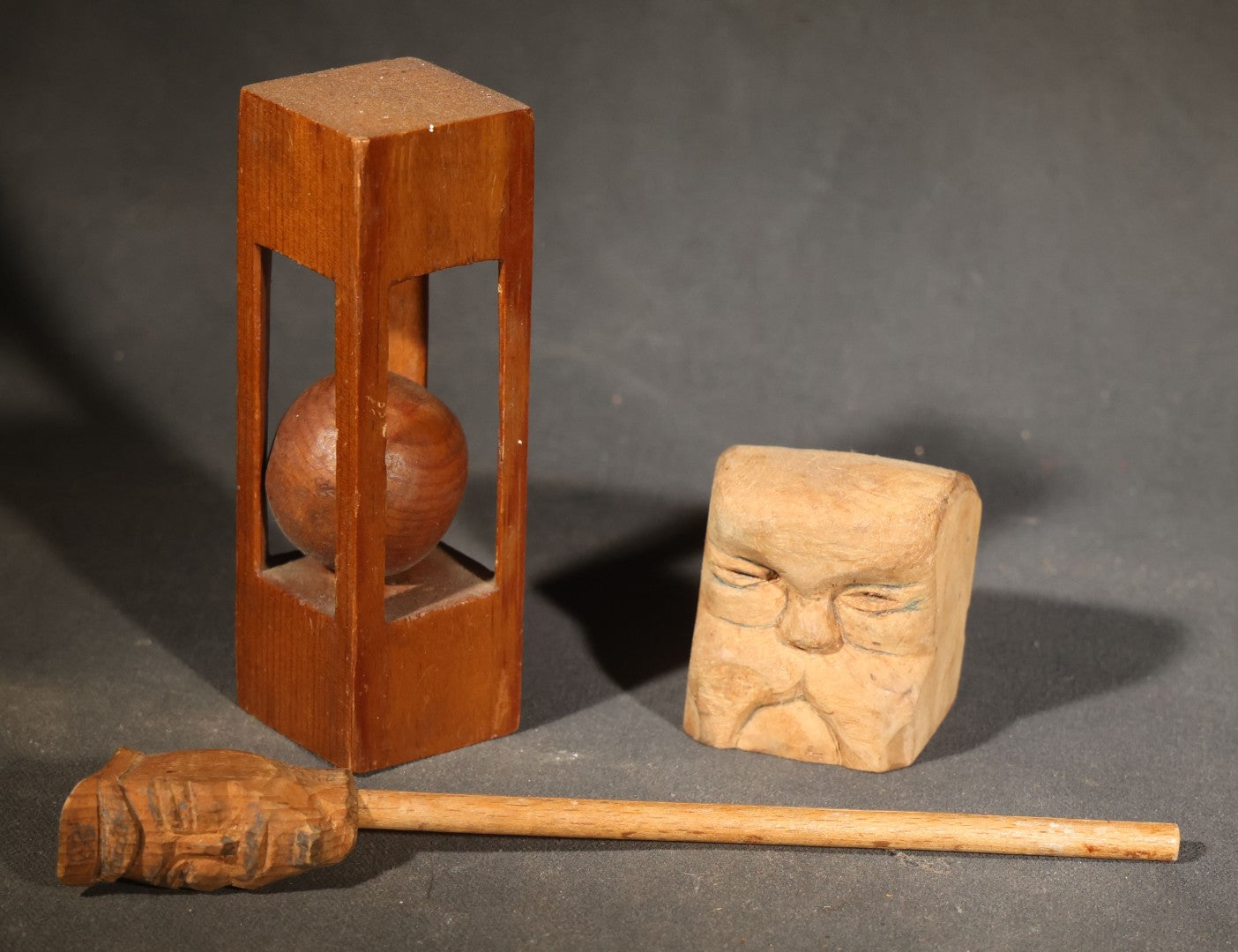 Grouping of Three Vintage Folk Art Wood Carvings including Ball-in-Cage Whimsy, Carved Face Block, and Carved Face on a Stick