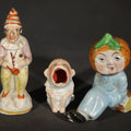 Lot 130 - Trio of Vintage Porcelain Figurines Including Clown with Violin, Open-Mouth Yawning Baby, and Orange-Head Child on Log