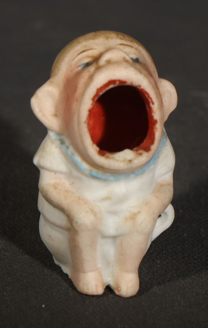 Trio of Vintage Porcelain Figurines including Clown with Violin, Open-Mouth Yawning Baby, and Orange-Head Child on Log