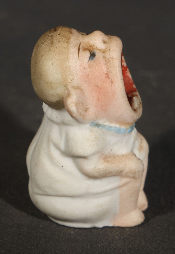 Trio of Vintage Porcelain Figurines including Clown with Violin, Open-Mouth Yawning Baby, and Orange-Head Child on Log