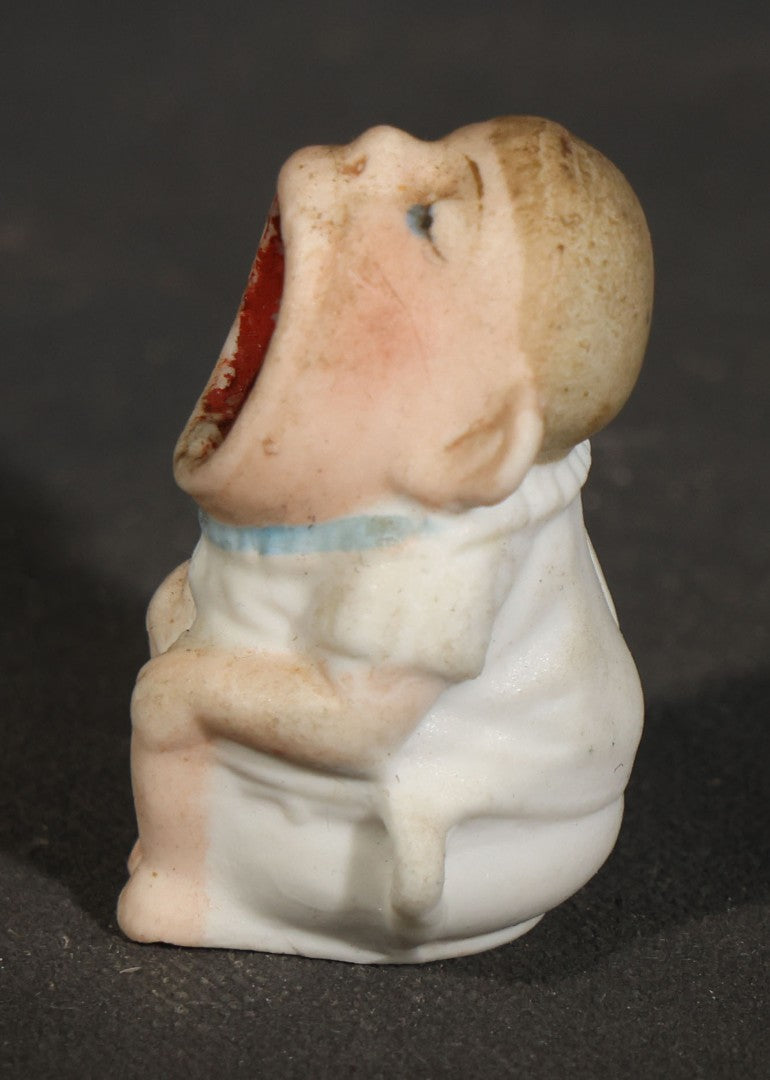 Trio of Vintage Porcelain Figurines including Clown with Violin, Open-Mouth Yawning Baby, and Orange-Head Child on Log