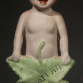 Lot 131 - Antique German Bisque Figurine of a Baby Holding a Green Leaf Inscribed "Guess What I Am", 6" H