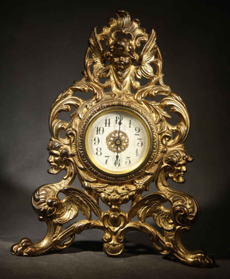 Antique Cast Brass Rococo Revival Style Mantel Clock with Winged Cherub, Grotesque Masks, and Scrolling Foliate Design, Signed A.F., Patented 1902-1908, Made in U.S.A.