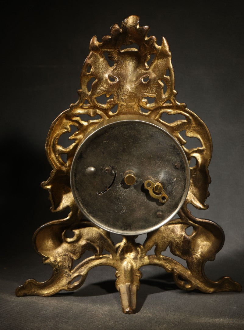 Antique Cast Brass Rococo Revival Style Mantel Clock with Winged Cherub, Grotesque Masks, and Scrolling Foliate Design, Signed A.F., Patented 1902-1908, Made in U.S.A.