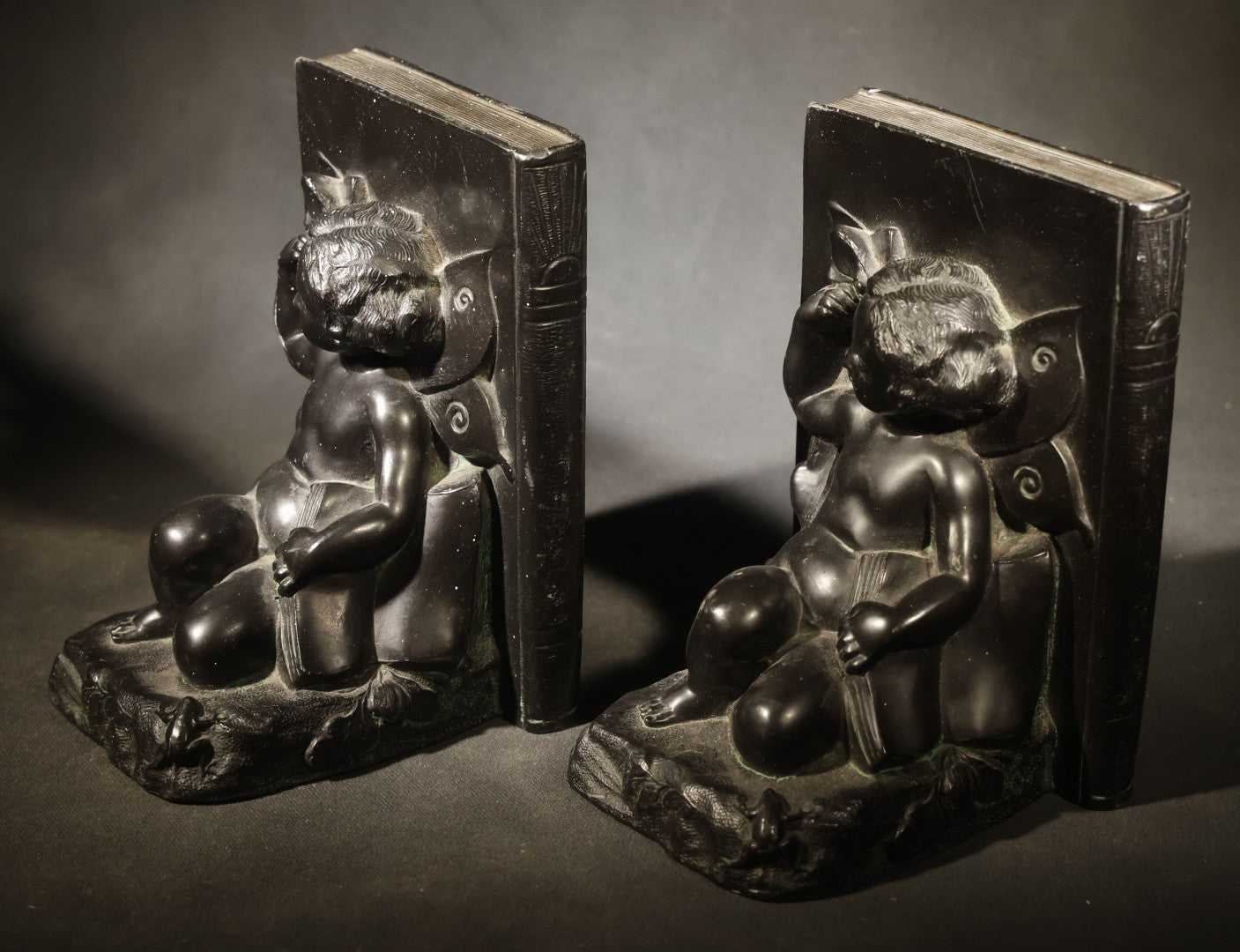 Pair of Antique Figural Bookends with Butterfly-Winged Child Seated Against Book-Form Back