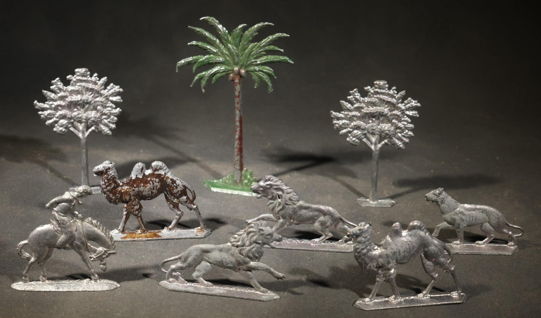 Grouping of Nine Antique German Zinnfiguren Flat Tin Figures including Camels, Lions, Bucking Bronco Rider, and Trees
