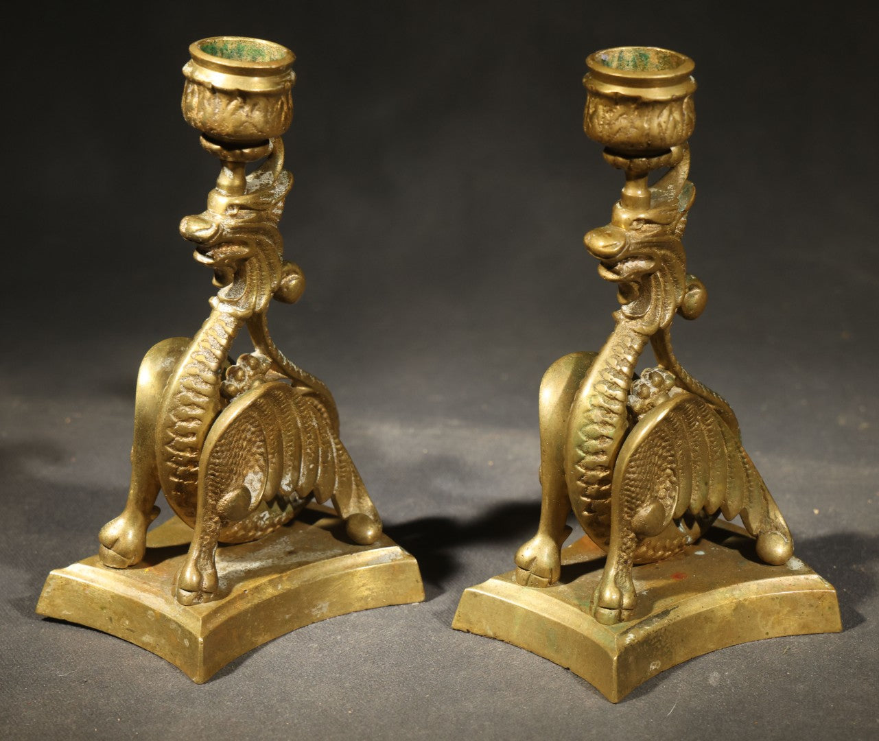 Pair of Antique Brass Figural Dragon or Griffin Candlesticks with Foliate Candle Cups on Shaped Bases