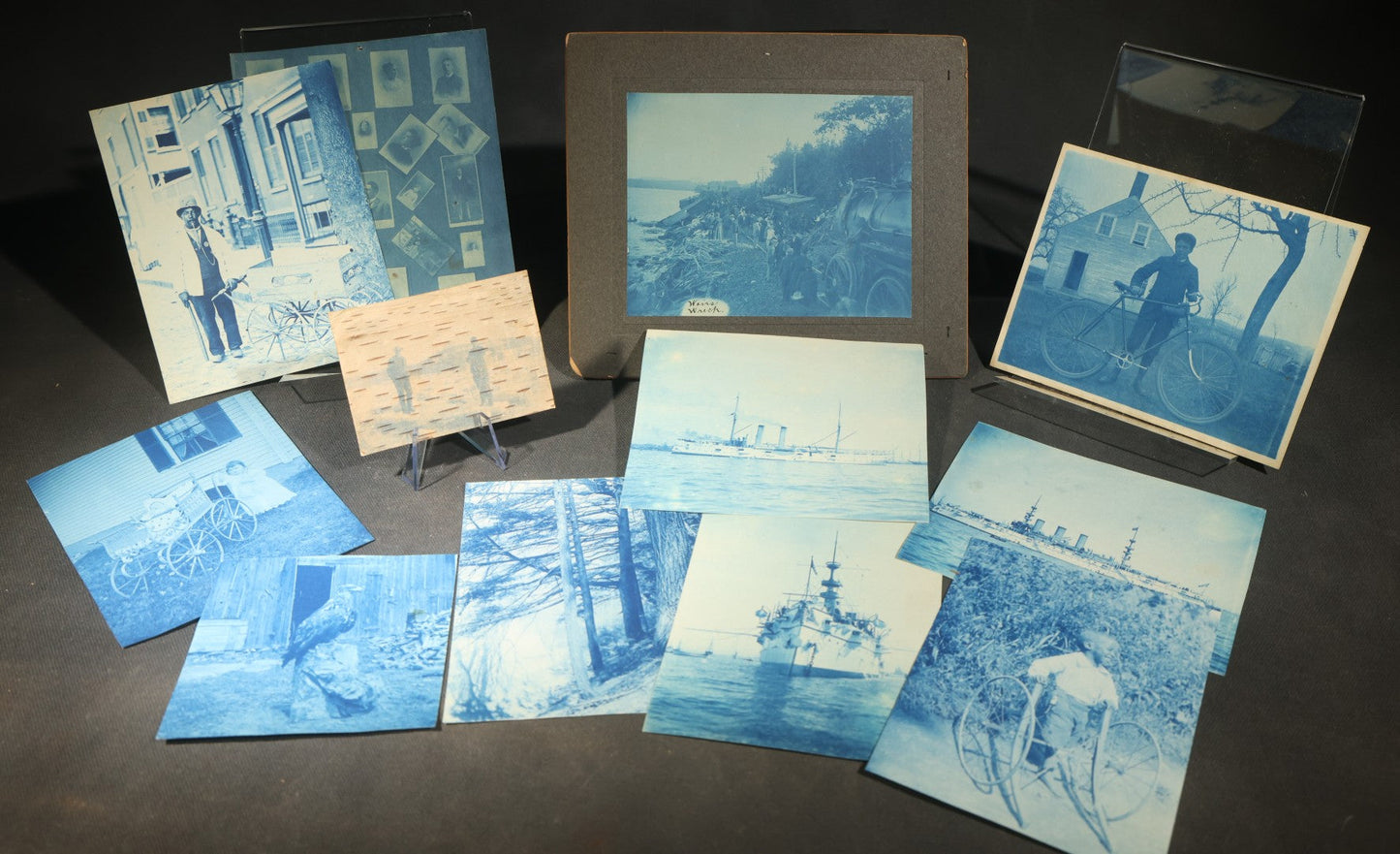 Grouping of 12 Antique Cyanotype Photographs including "Weirs Wreck" Train Derailment, Occupational Newspaper Deliveryman with "The Sun" Cart, Naval Warships, Cyanotype on Birch Bark, Man with Bicycle, and Photo Gallery Interior