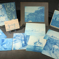 Lot 093 - Grouping of 12 Antique Cyanotype Photographs Including "Weirs Wreck" Train Derailment, Occupational Newspaper Deliveryman with "The Sun" Cart, Naval Warships, Cyanotype on Birch Bark, Man with Bicycle, and Photo Gallery Interior