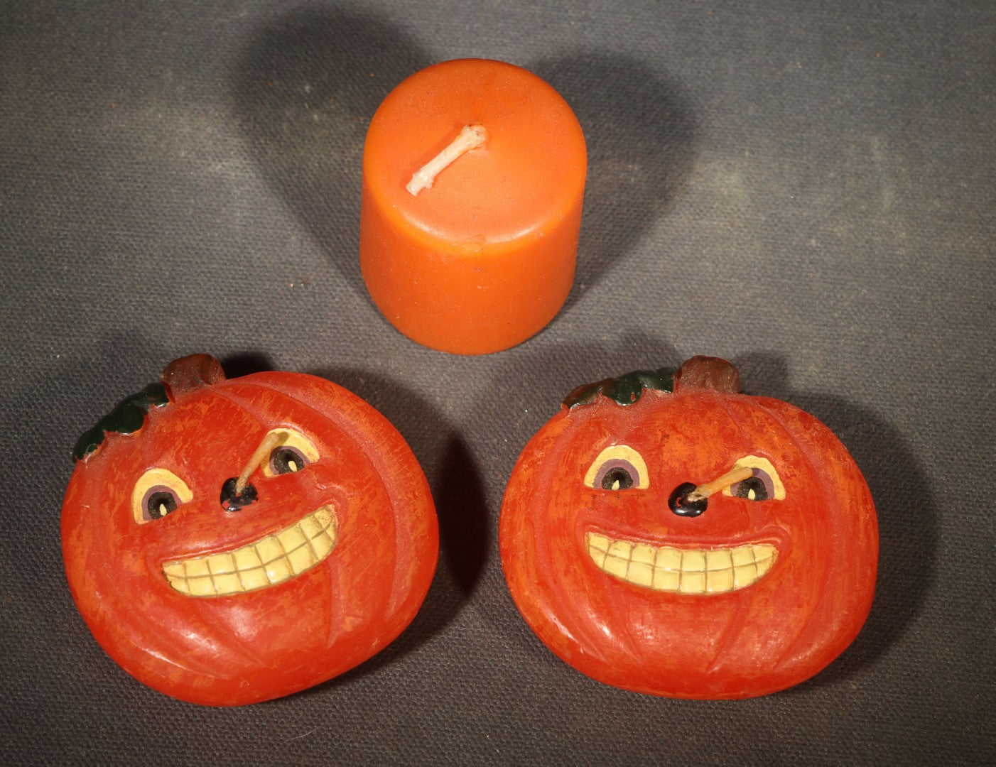 Grouping of Three Modern Halloween Candles including Two Grinning Jack-O-Lantern Pumpkin Figural Candles and One Orange Votive Candle