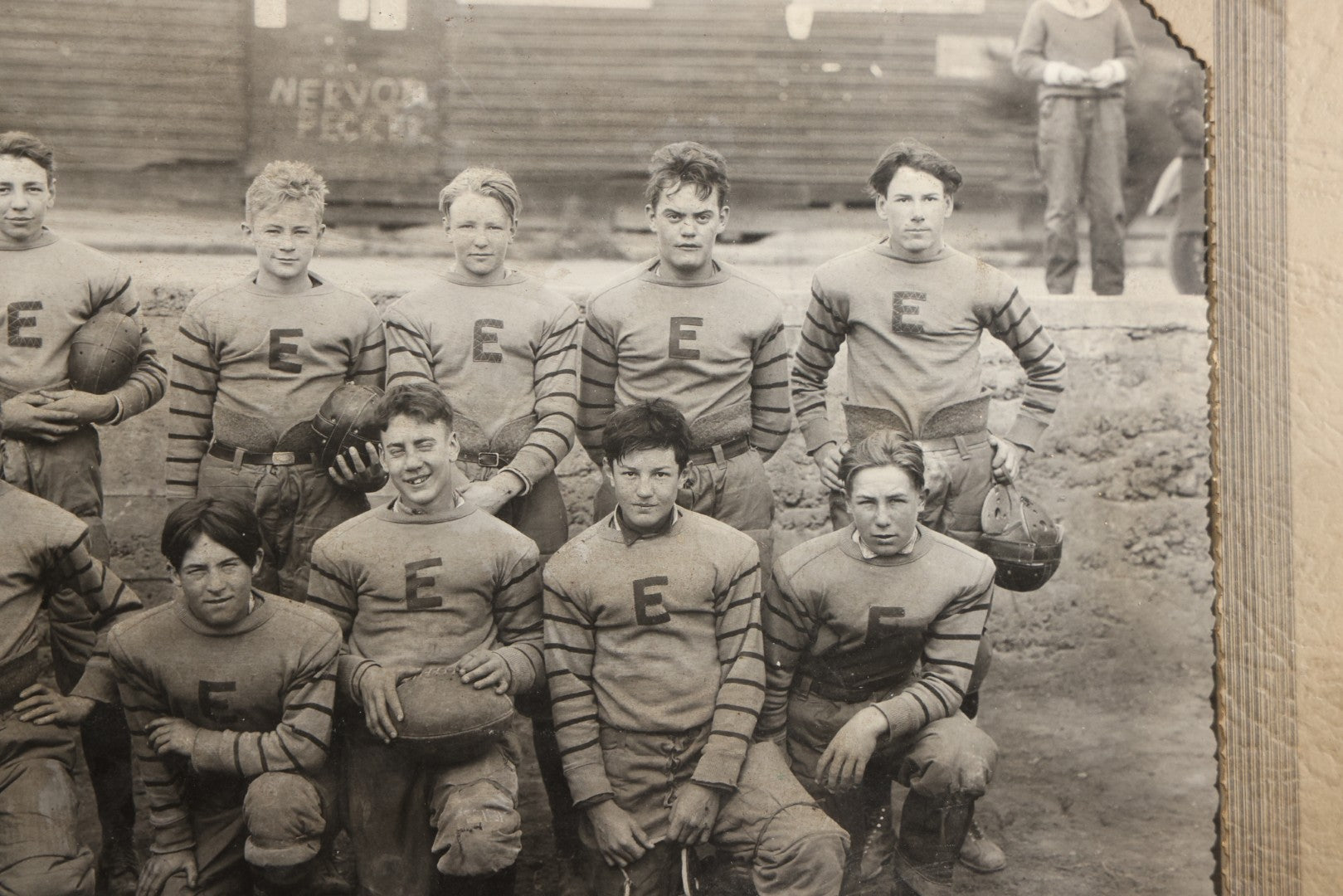 Antique Board-Mounted Photograph of a Football Team in "E" Letter Jerseys with Striped Sleeves, 12 Players with Leather Helmets and Footballs, Photographed by Photo Shop, Butte, Montana, Circa 1920s