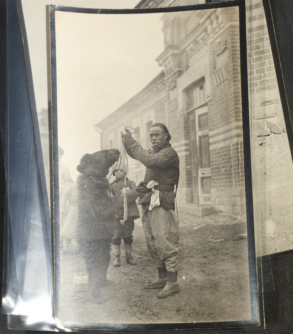 Grouping of 12 Antique Snapshot Photographs, East Asian and Russian-Language Settings including Sword Performer, Street Performer with Knife, Man with Trained Bear, Fishermen with Crabs, Construction Workers, and Children