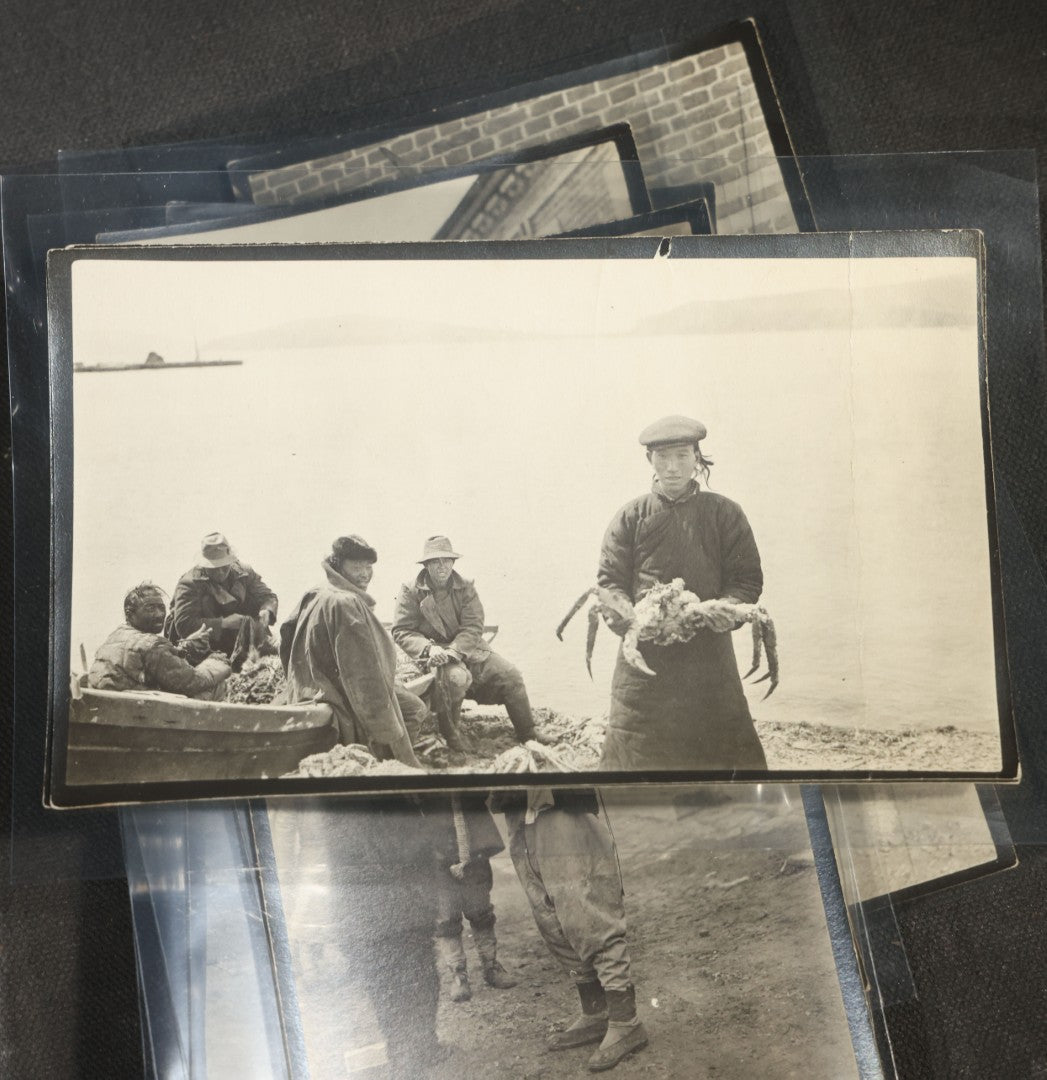 Grouping of 12 Antique Snapshot Photographs, East Asian and Russian-Language Settings including Sword Performer, Street Performer with Knife, Man with Trained Bear, Fishermen with Crabs, Construction Workers, and Children